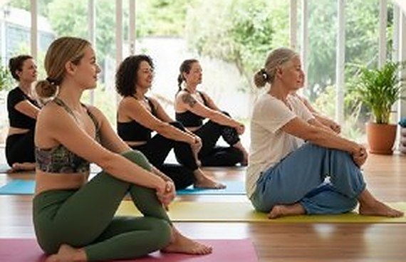 A yoga class seated on mats in a bright studio